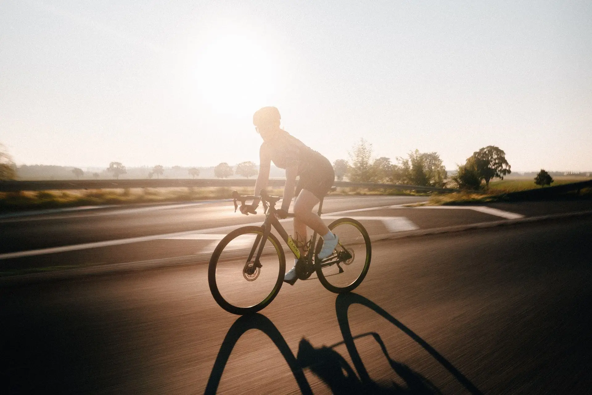 Rennradfahrer auf einer Landstraße im Gegenlicht